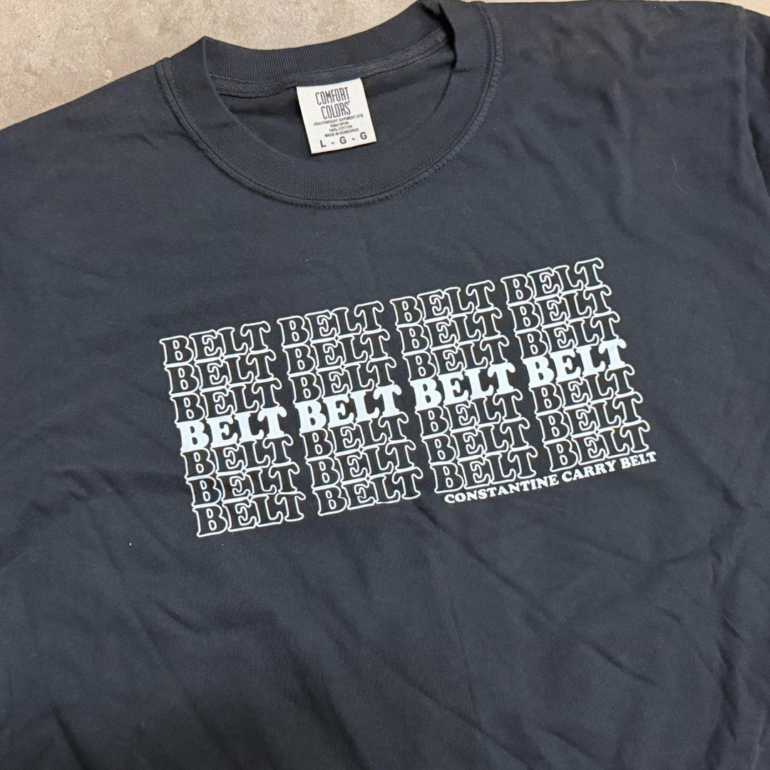 Black t-shirt with 'BELT' text pattern on a beige surface
