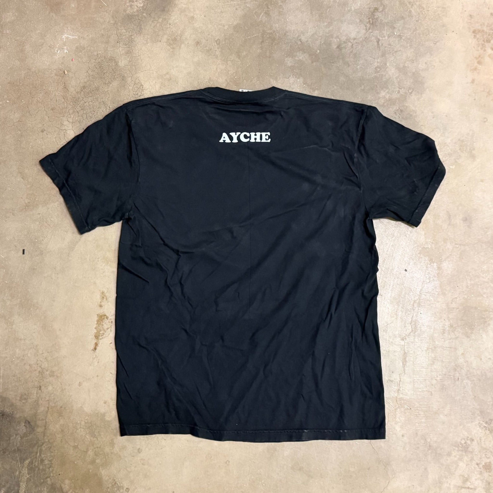 Black t-shirt with 'AYCHE' logo on a concrete floor