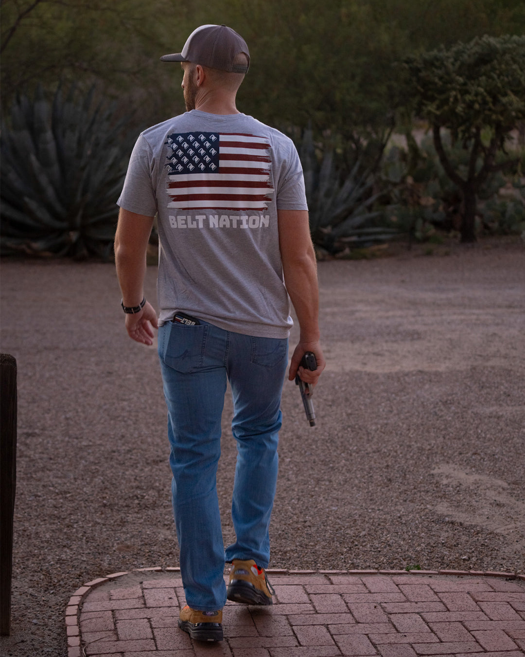 Man walking down a path in the Belt Flag Tee, back graphic showing