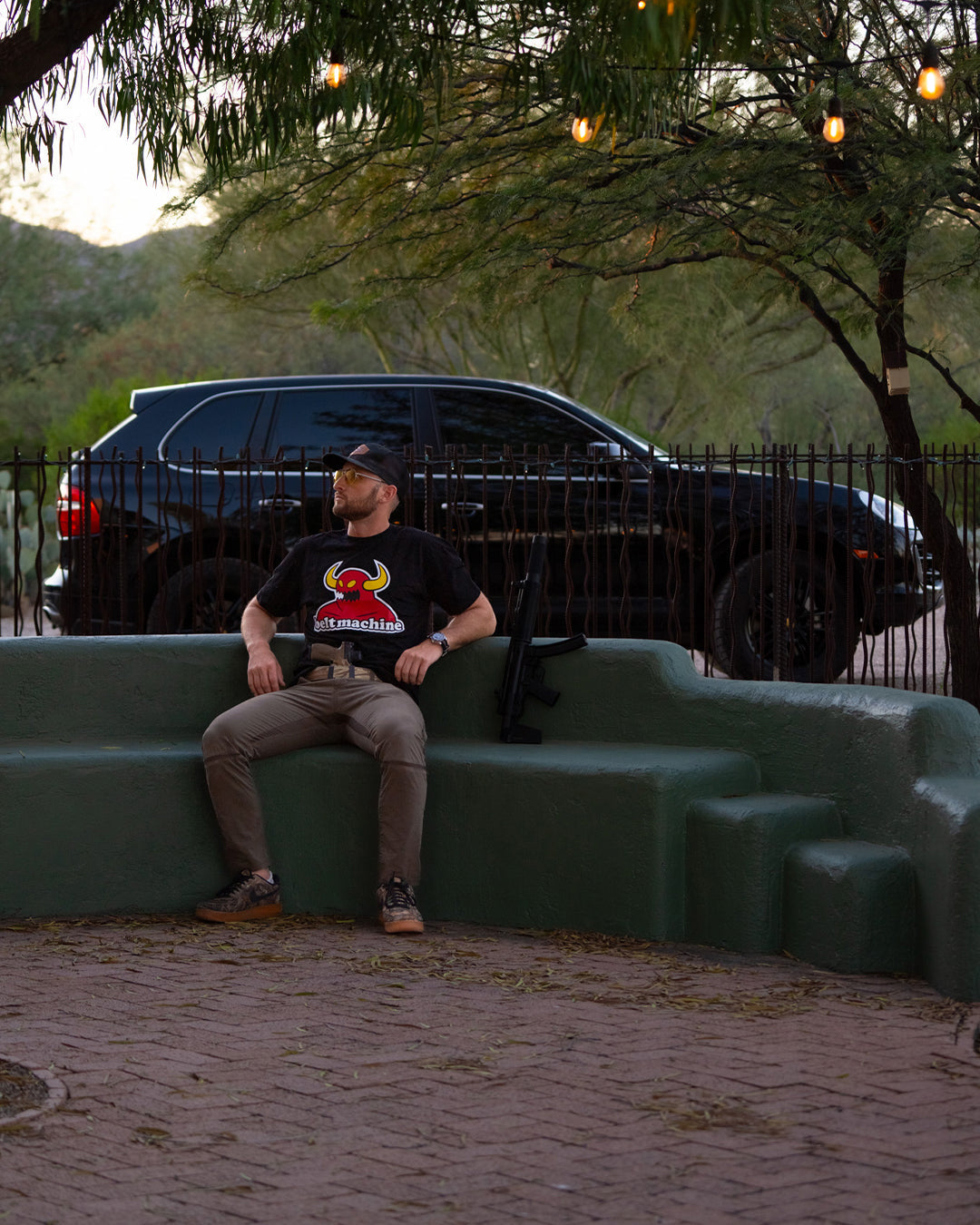Man sitting on an outdoor bench in the Belt Machine Tee