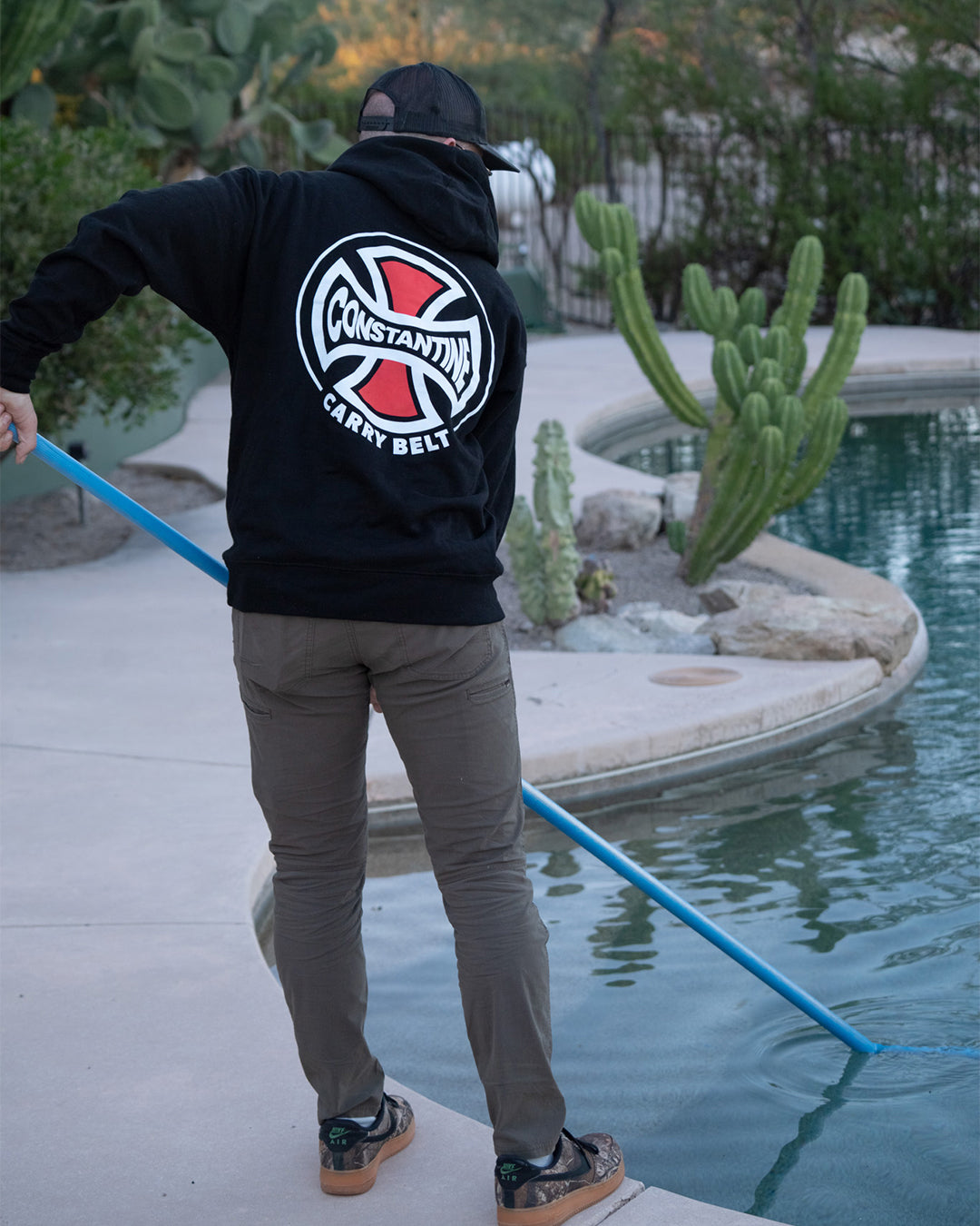 Man cleaning a pool in the Carry Belt Hood, back graphic showing
