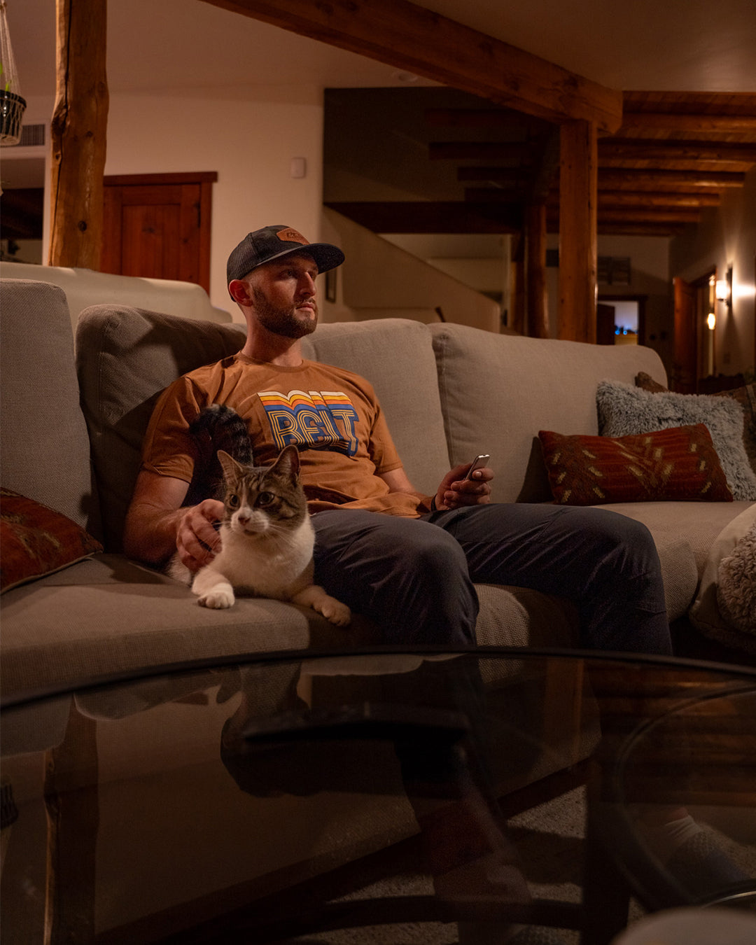 Man relaxing on a couch with his dog, wearing the Spectrum Belt Tee