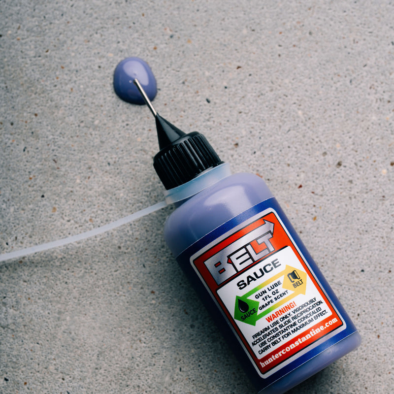 Bottle of BELG sauce with a dropper on a concrete surface