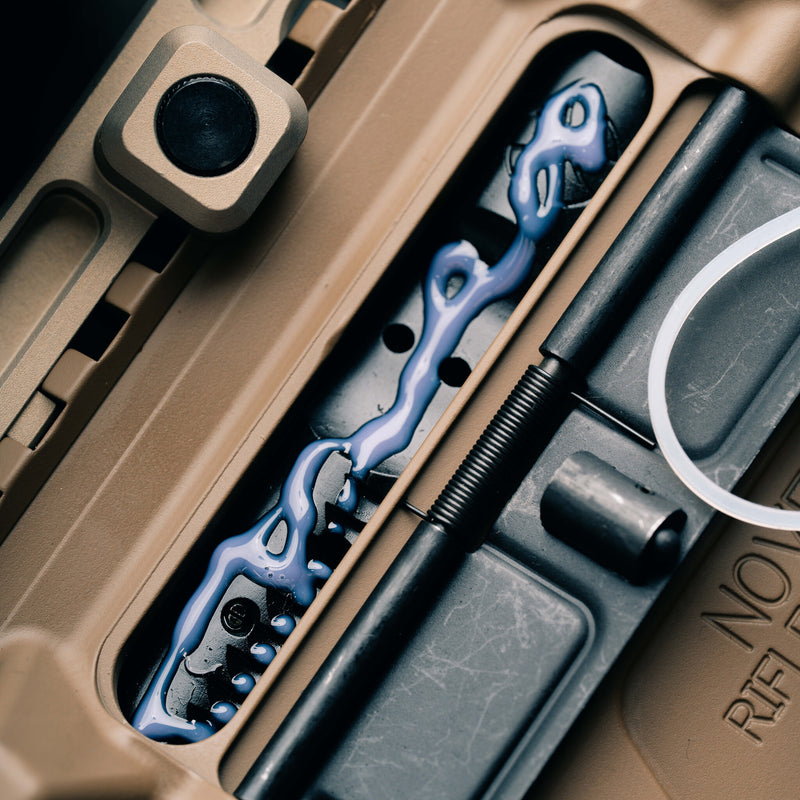 Close-up of a rifle's internal mechanism with blue lubricant.